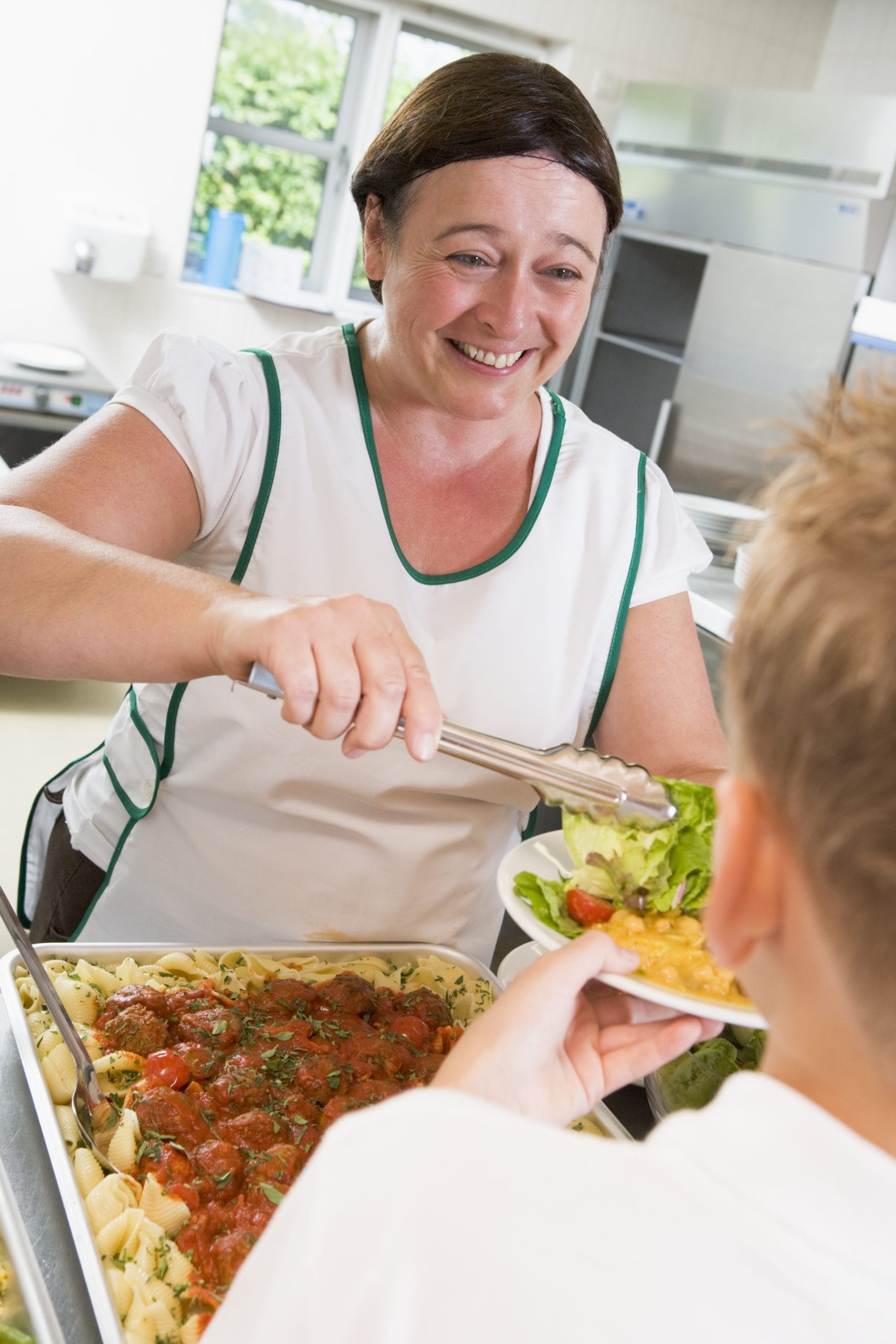Lunchlady serving plate of food in school cafeteria