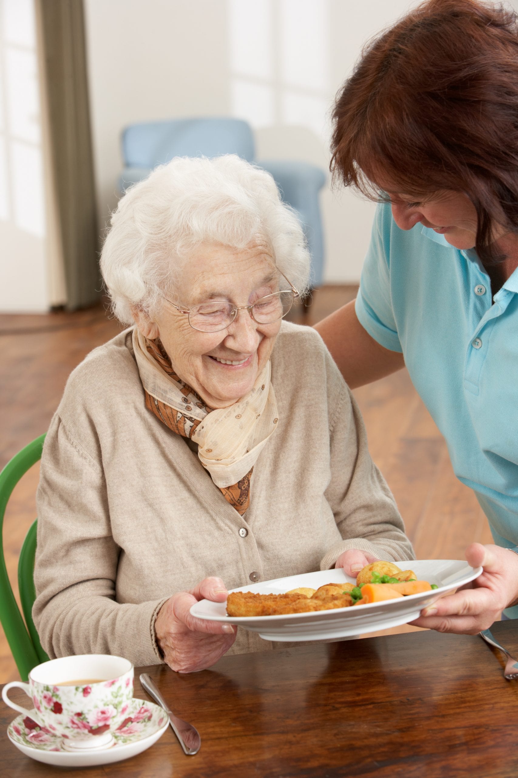 Seniorin bekommt gesundes Essen serviert von einer Pflegeperson